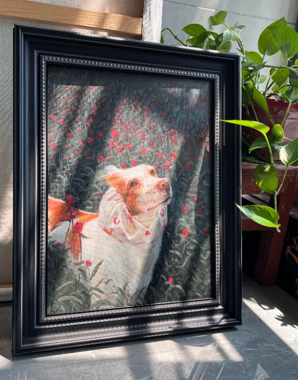 A smiling family posing with their dog, Sonny, and a beautiful framed oil portrait of another dog, Gabby, by Gabby, displayed in their home.